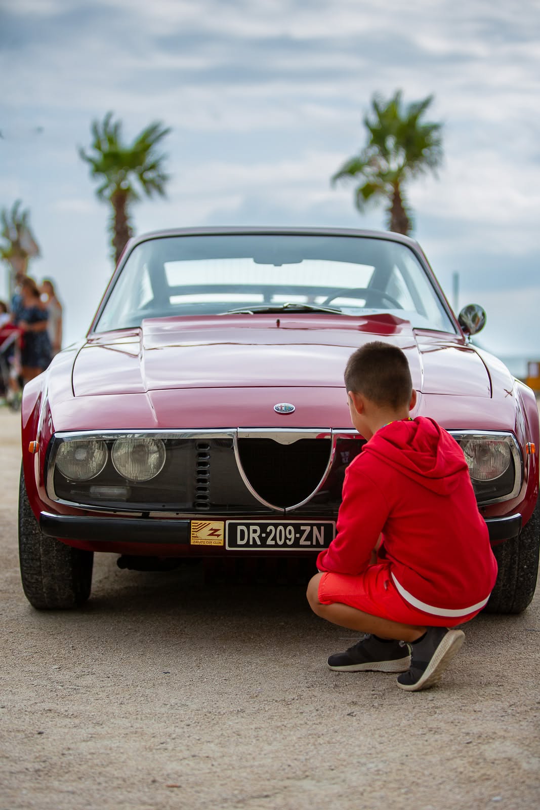 Alfa Romeo GTV rouge admiree par un enfant